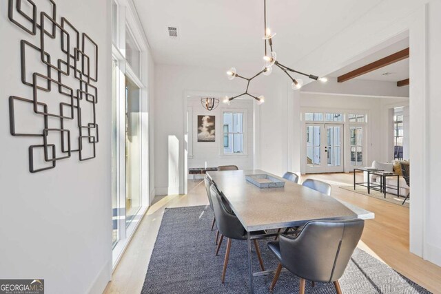 dining space featuring light hardwood / wood-style floors, french doors, beamed ceiling, and a chandelier