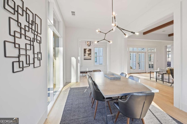 dining room featuring a chandelier, visible vents, baseboards, light wood-style floors, and french doors