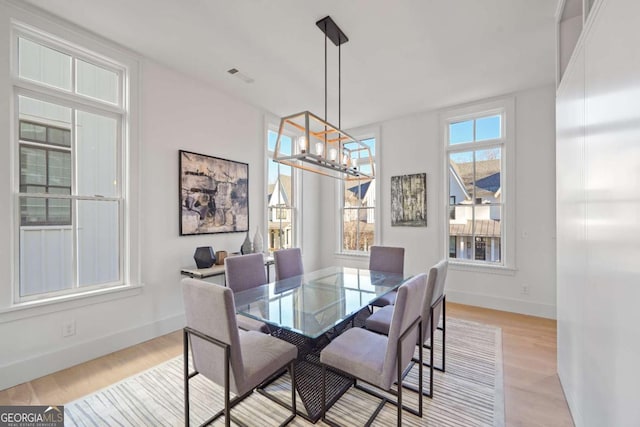 dining area featuring a chandelier, visible vents, light wood-style flooring, and baseboards