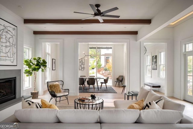 living room with ceiling fan, beamed ceiling, and light wood-type flooring