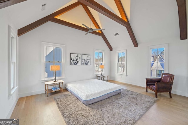 bedroom with high vaulted ceiling, light wood-type flooring, and multiple windows