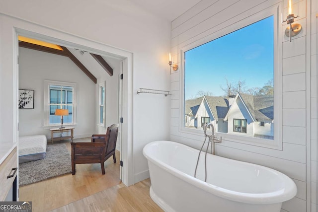 bathroom with lofted ceiling with beams, a bathing tub, and wood-type flooring