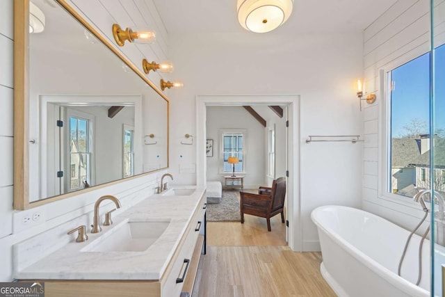 bathroom featuring vanity, wood-type flooring, plenty of natural light, and a bath