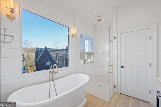 full bathroom with wood finished floors, a stall shower, and a freestanding tub