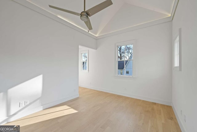 empty room with lofted ceiling, ceiling fan, light wood-style flooring, and baseboards