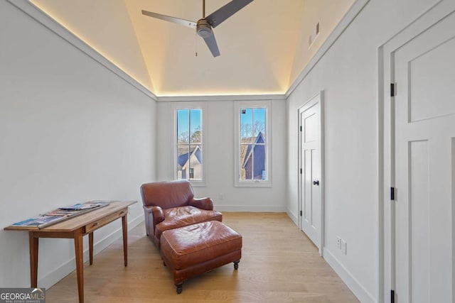 living area with ceiling fan, lofted ceiling, and light hardwood / wood-style floors