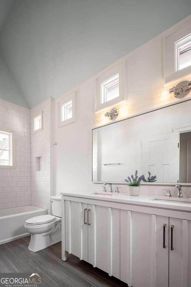 full bathroom with hardwood / wood-style floors, toilet, vanity, and lofted ceiling