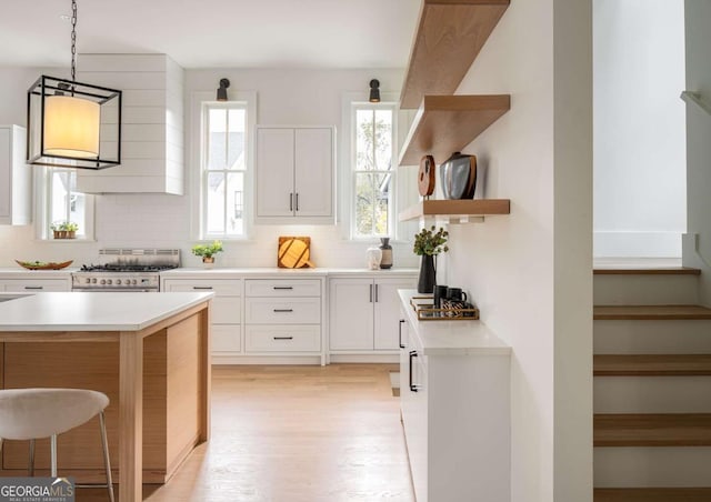 kitchen with white cabinets, decorative backsplash, pendant lighting, and high end stainless steel range oven