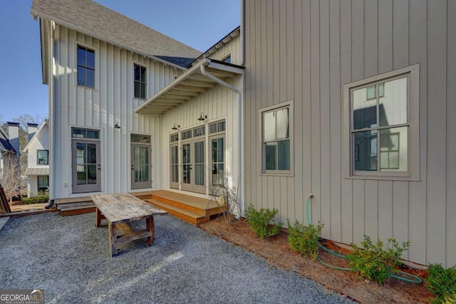 back of property with board and batten siding, french doors, and roof with shingles