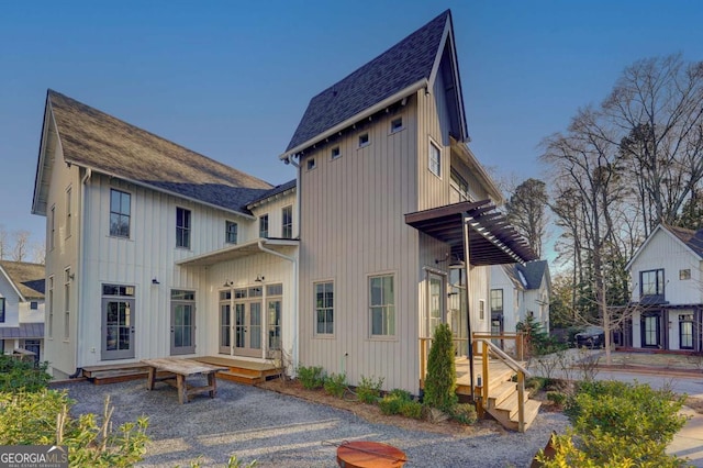 back of house featuring french doors and roof with shingles