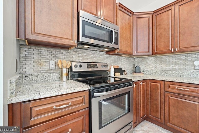 kitchen featuring backsplash, appliances with stainless steel finishes, and light stone counters