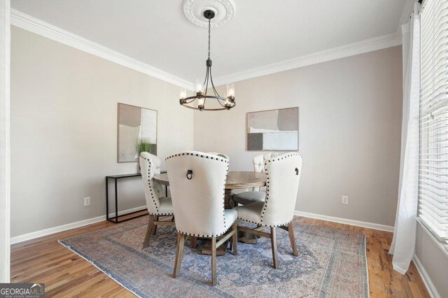 dining space with an inviting chandelier, ornamental molding, and wood-type flooring