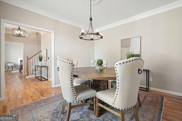 dining area with hardwood / wood-style flooring, ornamental molding, and an inviting chandelier