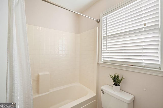 bathroom featuring toilet and shower / bath combination with curtain