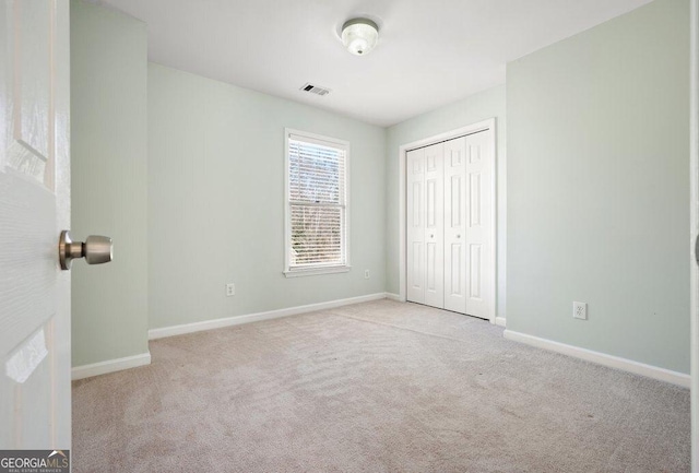 unfurnished bedroom with light colored carpet and a closet