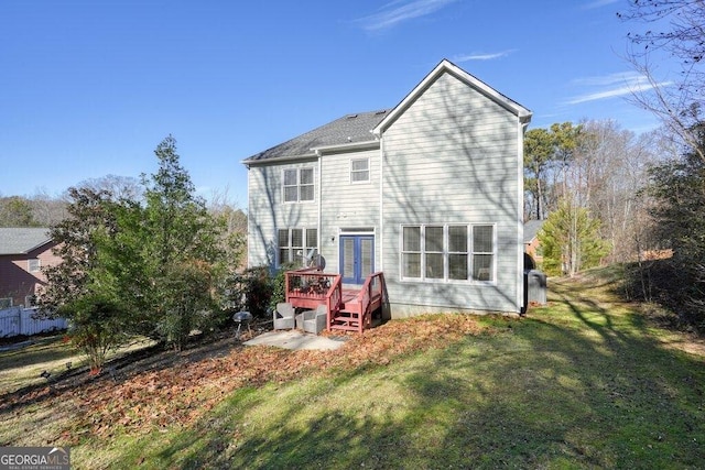 back of property with a wooden deck, french doors, a lawn, and a patio