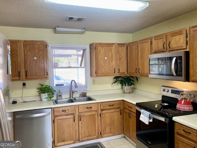 kitchen featuring stainless steel appliances, sink, and a textured ceiling