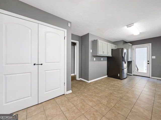 kitchen featuring stainless steel refrigerator with ice dispenser, light tile patterned flooring, and a textured ceiling