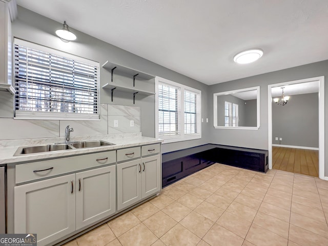 kitchen with decorative light fixtures, a notable chandelier, decorative backsplash, sink, and light tile patterned floors