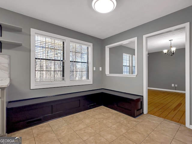 empty room with light tile patterned floors and a chandelier