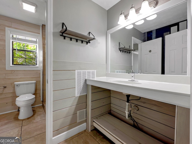 bathroom featuring sink, tile patterned floors, toilet, and wooden walls