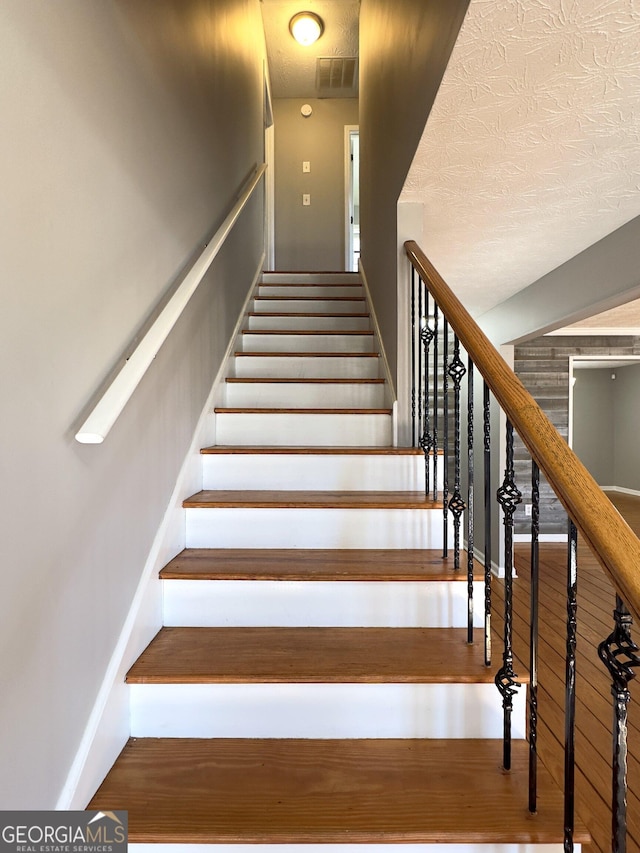 stairway featuring hardwood / wood-style flooring and a textured ceiling