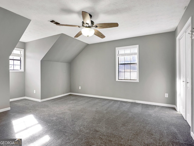 additional living space with ceiling fan, plenty of natural light, dark carpet, and lofted ceiling