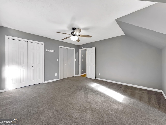 unfurnished bedroom featuring ceiling fan, lofted ceiling, carpet floors, and two closets