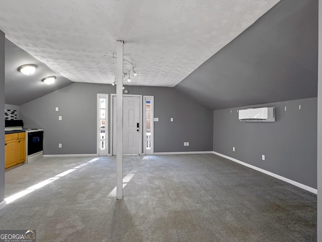 additional living space featuring a textured ceiling, lofted ceiling, carpet floors, and a wall mounted air conditioner