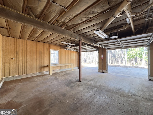 garage featuring a garage door opener and wooden walls