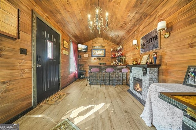 interior space with vaulted ceiling, wooden ceiling, light hardwood / wood-style floors, and wood walls