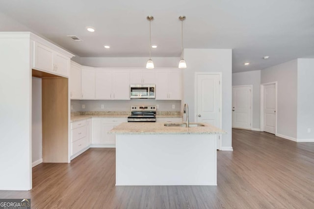 kitchen featuring stainless steel appliances, a kitchen island with sink, hanging light fixtures, white cabinets, and sink