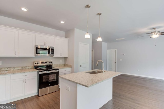 kitchen featuring white cabinetry, stainless steel appliances, a kitchen island with sink, decorative light fixtures, and sink