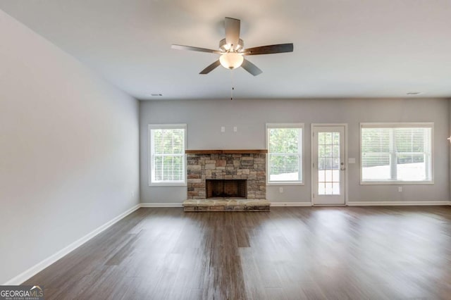 unfurnished living room with dark hardwood / wood-style floors, ceiling fan, a fireplace, and plenty of natural light