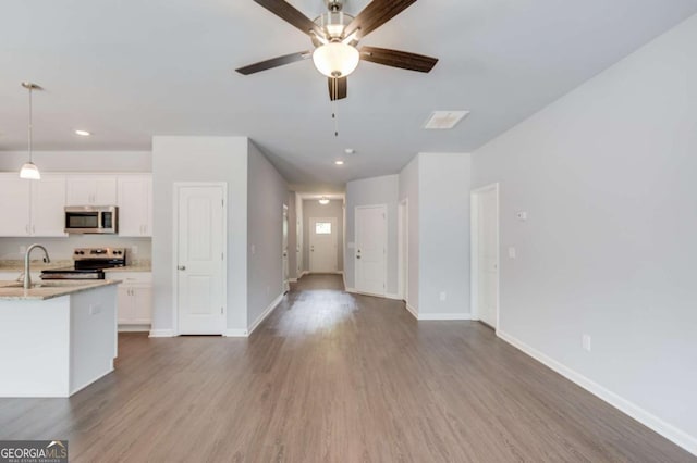 kitchen featuring light stone countertops, white cabinets, appliances with stainless steel finishes, sink, and hanging light fixtures