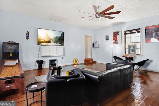 living room with a textured ceiling, ceiling fan, and dark hardwood / wood-style flooring