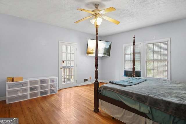 bedroom with a textured ceiling, ceiling fan, and wood-type flooring