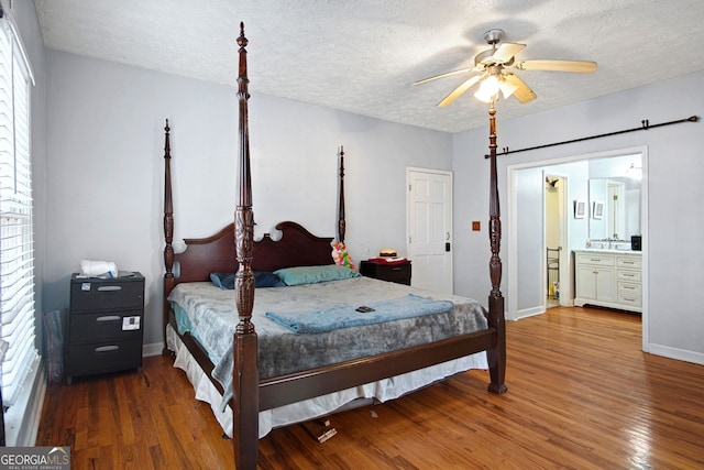 bedroom featuring ceiling fan, a textured ceiling, hardwood / wood-style flooring, and connected bathroom