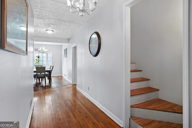 interior space featuring a textured ceiling, hardwood / wood-style floors, and a notable chandelier