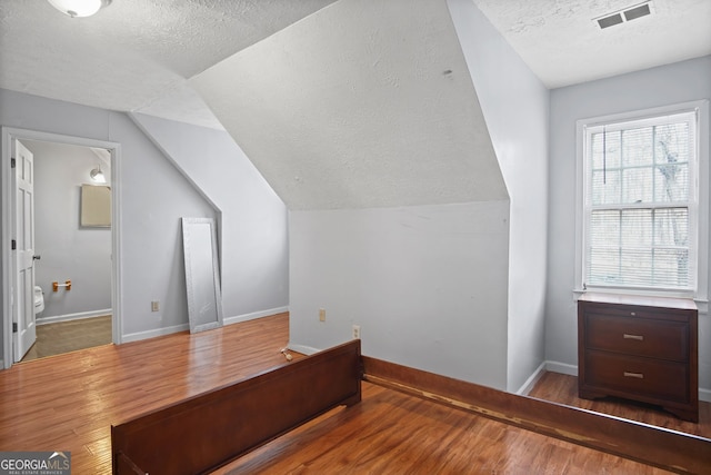 bonus room with hardwood / wood-style flooring, a textured ceiling, and vaulted ceiling