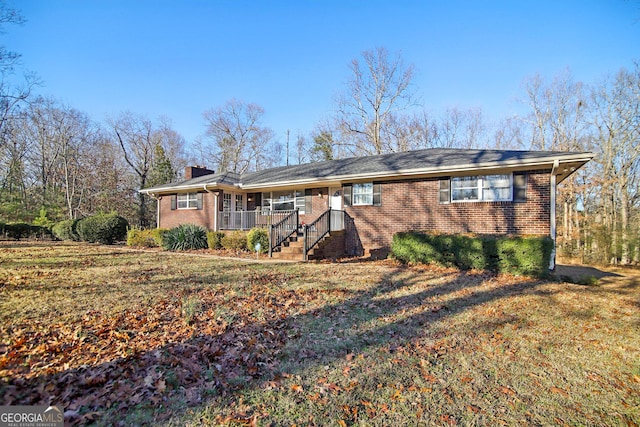 ranch-style house featuring covered porch and a front yard