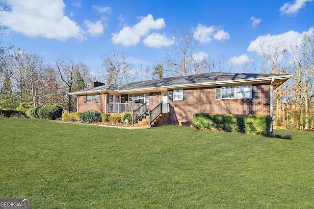 view of front facade with brick siding, a porch, and a front yard