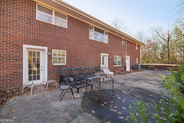 back of property with central air condition unit and a patio