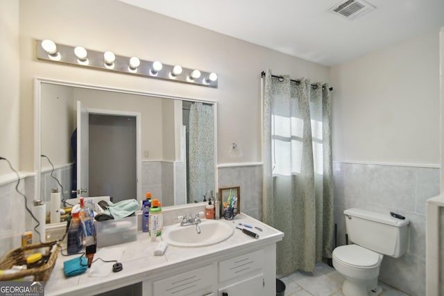 bathroom featuring toilet, tile walls, tile patterned floors, and vanity