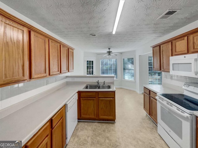 kitchen featuring kitchen peninsula, ceiling fan, tasteful backsplash, white appliances, and sink