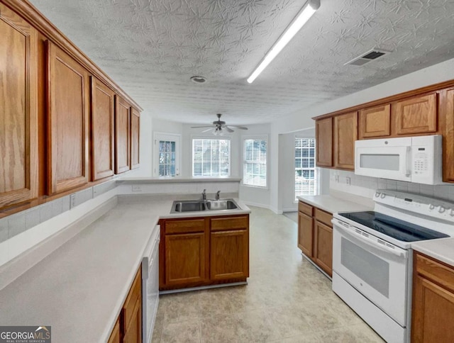 kitchen with ceiling fan, backsplash, sink, and white appliances