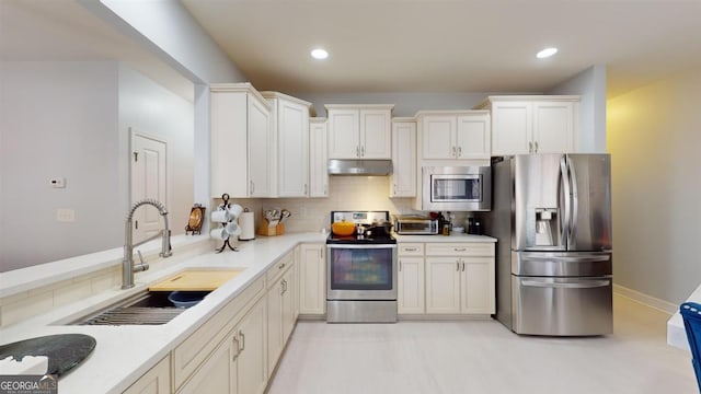 kitchen featuring backsplash, sink, stainless steel appliances, and white cabinetry