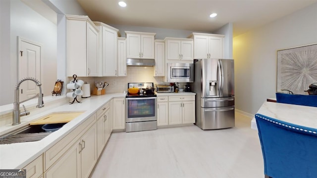 kitchen with tasteful backsplash, white cabinets, sink, and stainless steel appliances