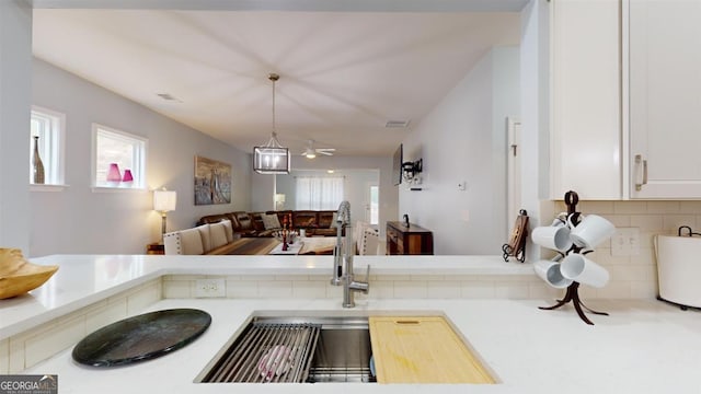 kitchen featuring ceiling fan, backsplash, white cabinetry, and hanging light fixtures