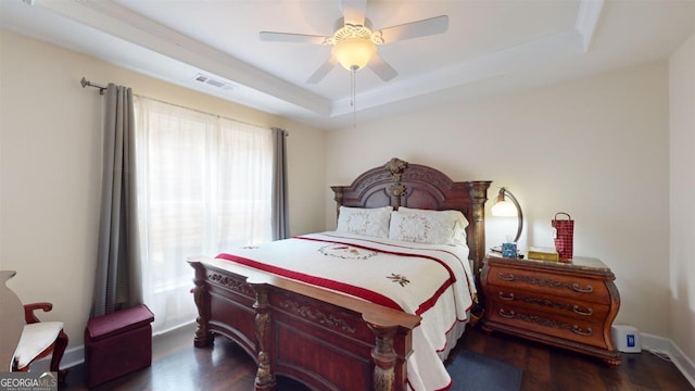 bedroom with dark hardwood / wood-style floors, ceiling fan, and a raised ceiling